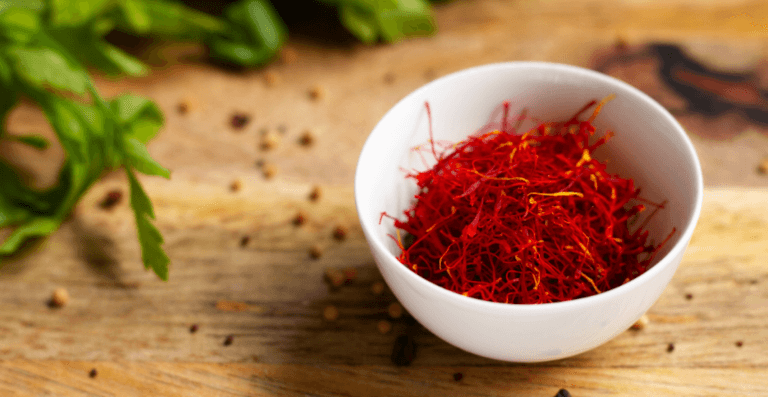 close-shot-of-a-white-bowl-of-a-premium-saffron-with-green-leaves-aside