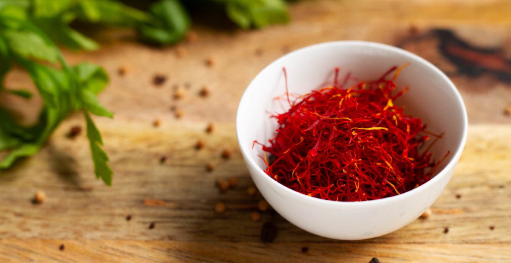 close-shot-of-a-white-bowl-of-a-premium-saffron-with-green-leaves-aside